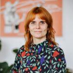 Rothaarige Frau lächelt in die Kamera.