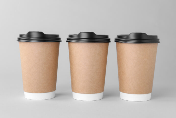 Paper cups with black lids on light grey background.