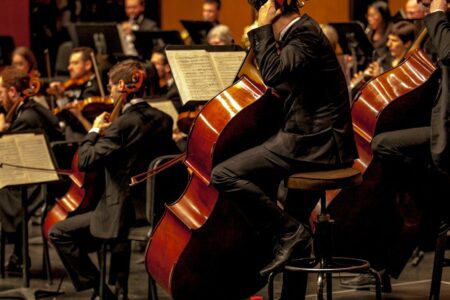 An orchestra photographed from the side, cellists in the foreground.