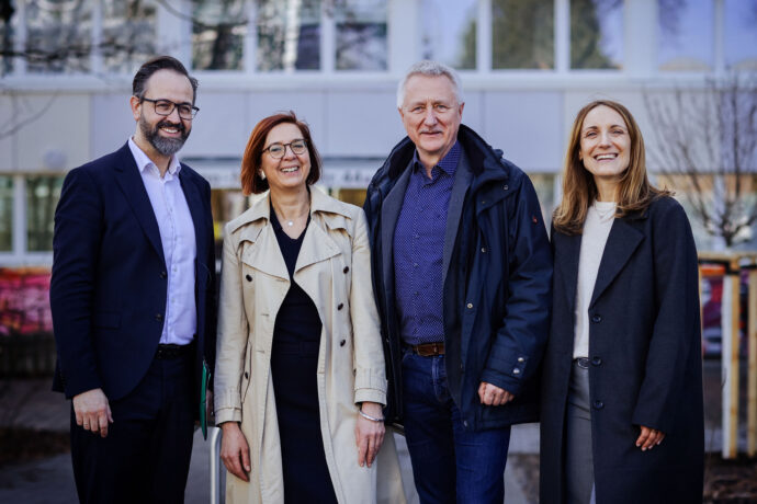Vier Menschen stehen vor einem Wohnheim für Studierende.