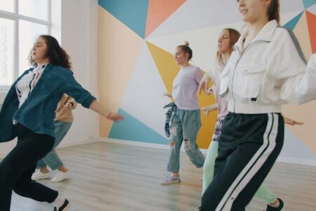 Junge Menschen, die eine Choreografie tanzen. Dynamische Bewegungen, die vordere Frau ist angeschnitten